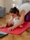 A mother doing post-pregnancy skin tightening exercises at home on a yoga mat, bonding with her baby nearby.